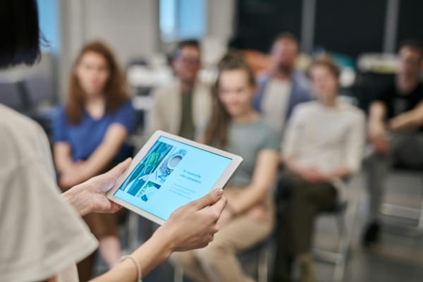 A person presenting holding a tablet. 