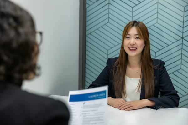 Woman sitting at the table with a piece of resume paper in front of her.